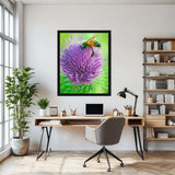 Framed photograph of a bee on a purple flower above a desk in a home office.