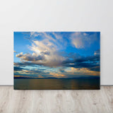 Canvas print of a sunset over a body of water with clouds.