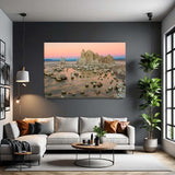 Living room with a large wall-mounted canvas displaying a natural landscape, a white sofa with pillows, a coffee table, and a plant.