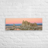 Panorama of tufa formations and water at sunset against a white brick wall.