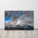 Mountain range with snow under a cloudy sky on a wooden surface.