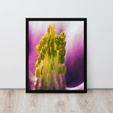 Framed photograph of a yellow flower with a purple background on a white wall.